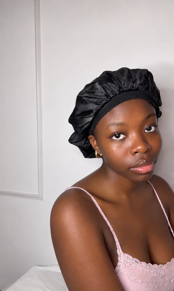 Client in a pink lace cami and black satin bonnet, fresh glowing skin