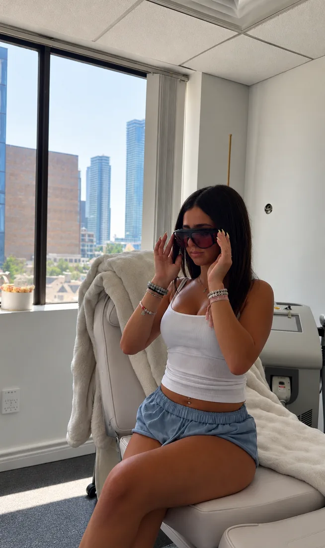 Client wearing laser-safety goggles in a bright treatment room overlooking the city skyline